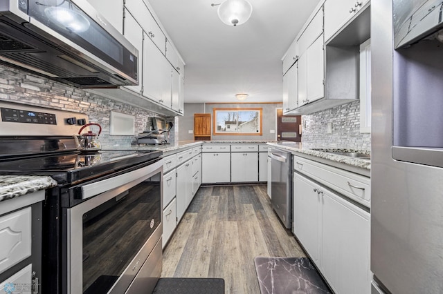 kitchen with light stone counters, light hardwood / wood-style flooring, backsplash, white cabinets, and appliances with stainless steel finishes