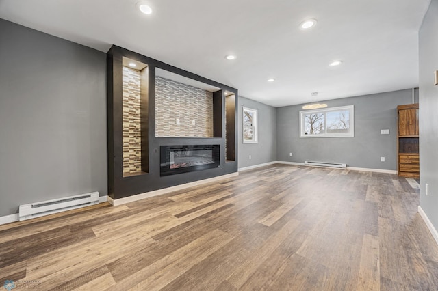 unfurnished living room with wood-type flooring, a fireplace, and a baseboard heating unit