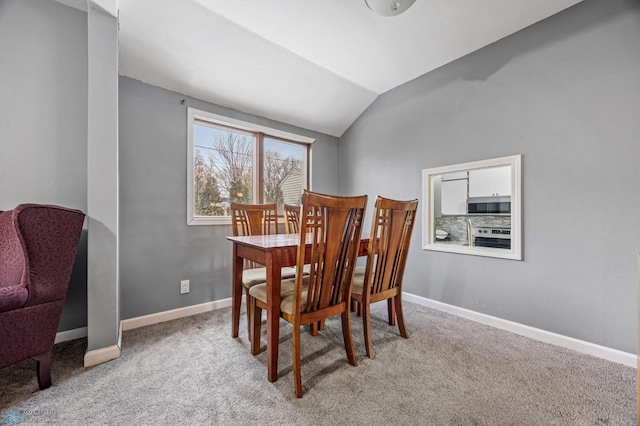 dining area featuring light carpet and vaulted ceiling