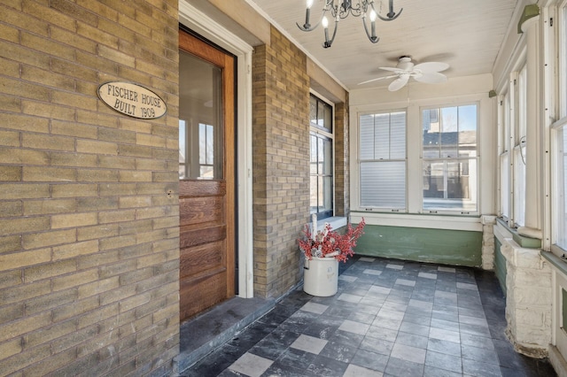 unfurnished sunroom featuring ceiling fan with notable chandelier