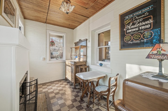 dining space with brick wall and wooden ceiling