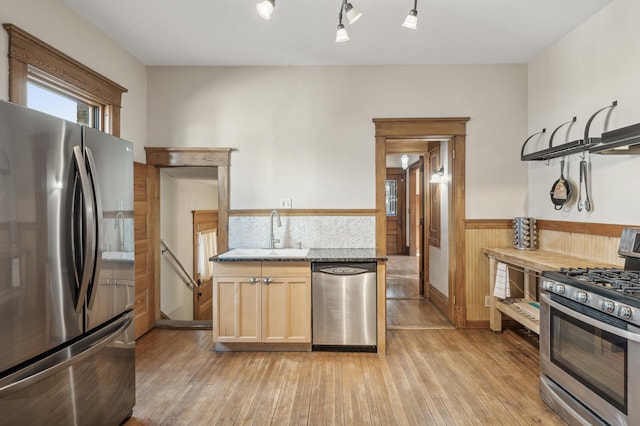 kitchen featuring appliances with stainless steel finishes, light brown cabinetry, sink, light stone counters, and light hardwood / wood-style flooring