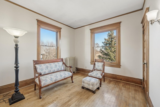 sitting room featuring radiator, ornamental molding, hardwood / wood-style floors, and a healthy amount of sunlight