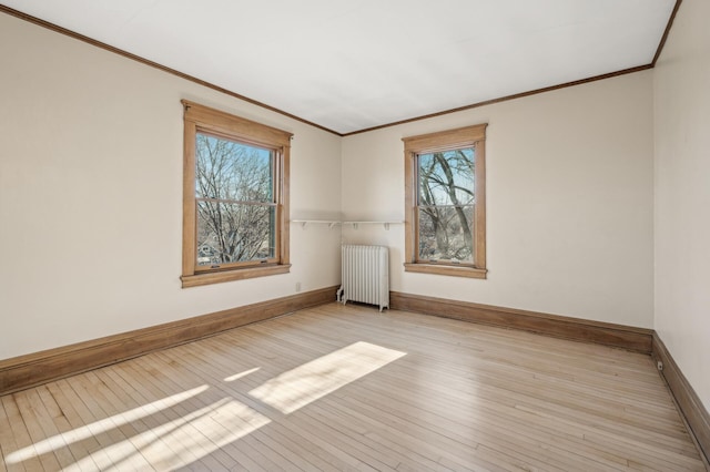 empty room with ornamental molding, radiator, and light wood-type flooring