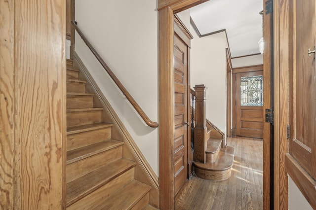 stairs with crown molding and hardwood / wood-style flooring