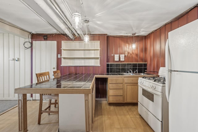 kitchen featuring pendant lighting, white appliances, a kitchen bar, tile countertops, and light wood-type flooring