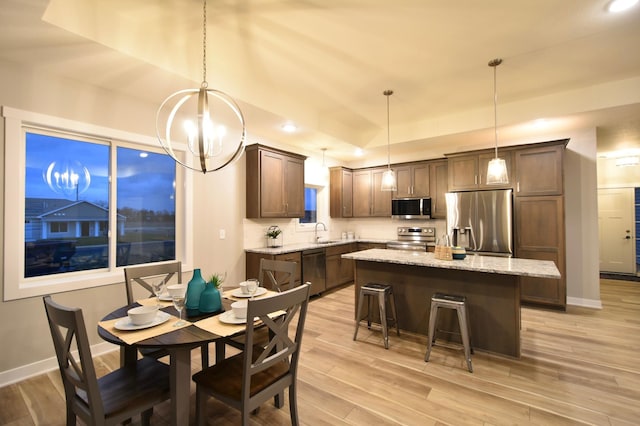 dining area with sink, an inviting chandelier, and light wood-type flooring