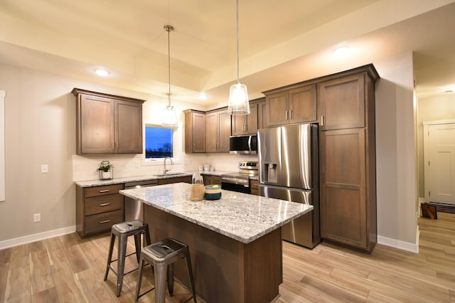 kitchen featuring a center island, light hardwood / wood-style flooring, decorative light fixtures, and appliances with stainless steel finishes