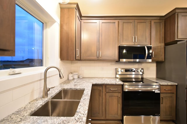 106 Fairway St, Zumbrota, MN 55992 - kitchen featuring stainless steel appliances, a sink, decorative backsplash, and light stone countertops