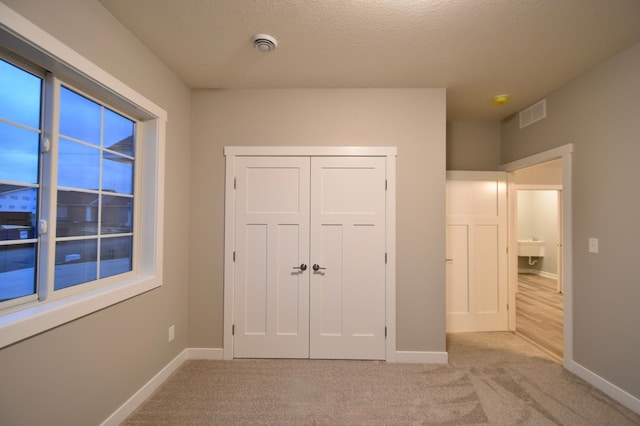 106 Fairway St, Zumbrota, MN 55992 - unfurnished bedroom with baseboards, light carpet, a textured ceiling, and a closet