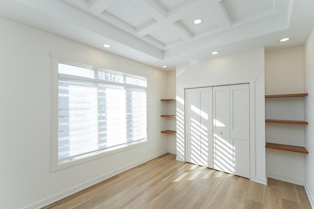 interior space featuring beam ceiling, light wood-type flooring, a closet, and coffered ceiling