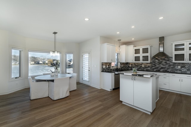 kitchen featuring white cabinetry, a center island, and wall chimney range hood