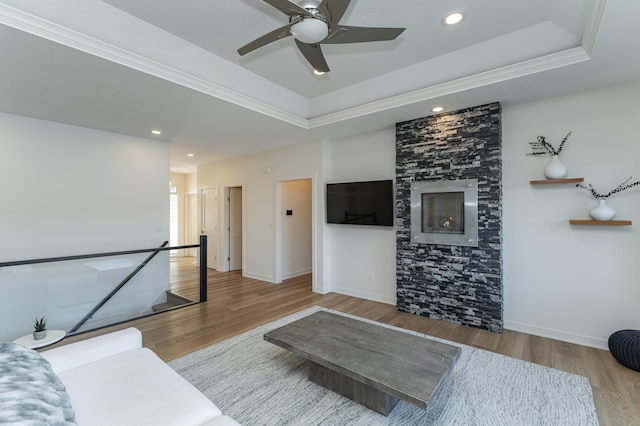 living room featuring hardwood / wood-style flooring, a raised ceiling, and a fireplace