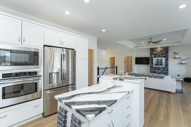 kitchen featuring white cabinets, stainless steel appliances, a raised ceiling, and a kitchen island