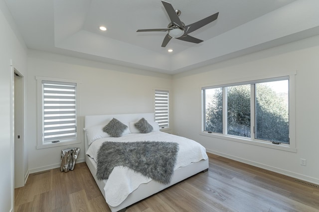 bedroom featuring a tray ceiling, ceiling fan, and wood-type flooring