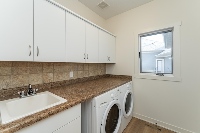 washroom with hardwood / wood-style floors, washer and dryer, cabinets, and sink