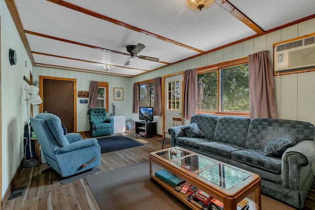 living area with visible vents, beamed ceiling, an AC wall unit, and wood finished floors