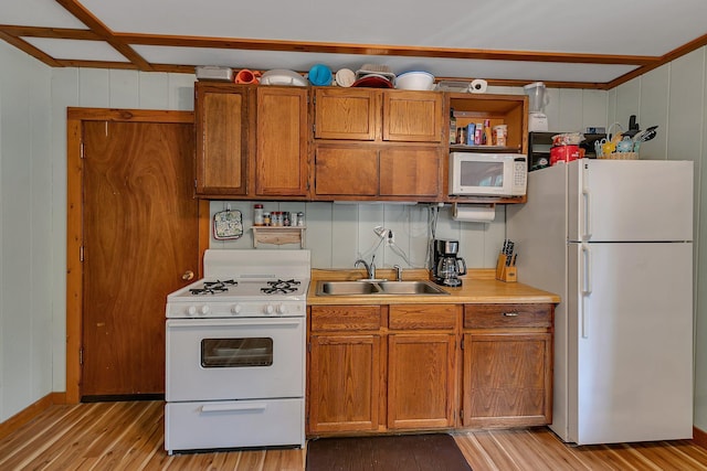 kitchen featuring white appliances, brown cabinets, a sink, light countertops, and light wood-type flooring