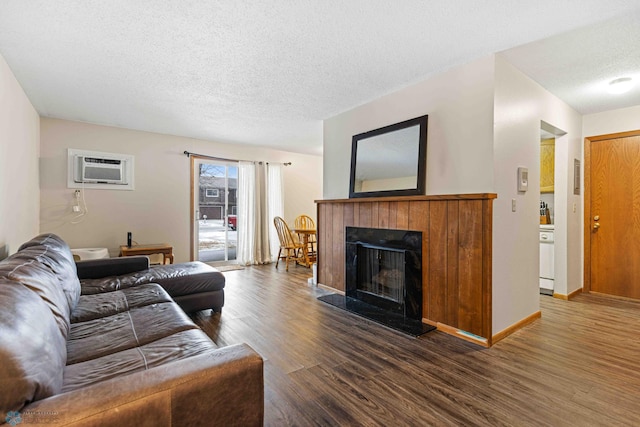 living room with an AC wall unit, dark hardwood / wood-style flooring, and a textured ceiling