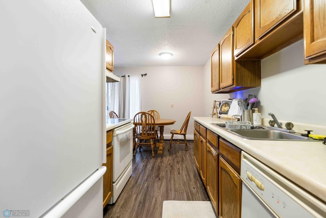 kitchen with a textured ceiling, dark hardwood / wood-style flooring, white appliances, and sink