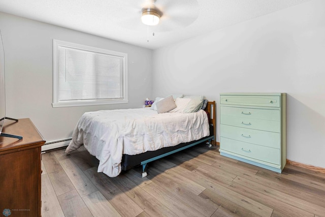 bedroom featuring baseboard heating, ceiling fan, and light wood-type flooring