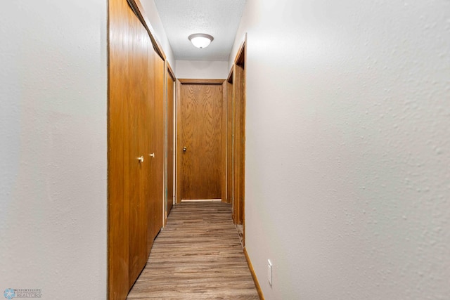 corridor featuring a textured ceiling and light wood-type flooring