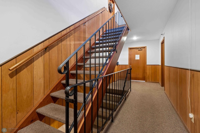 stairway featuring carpet floors and wood walls