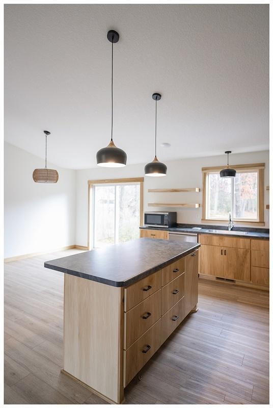 kitchen featuring stainless steel appliances, hanging light fixtures, a center island, and light hardwood / wood-style floors