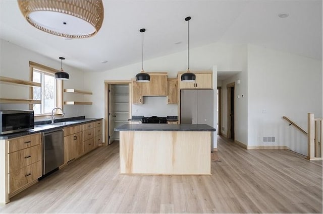 kitchen with a kitchen island, light wood-type flooring, lofted ceiling, and appliances with stainless steel finishes