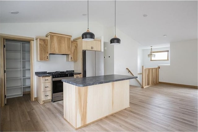 kitchen with light brown cabinetry, stainless steel appliances, vaulted ceiling, pendant lighting, and light hardwood / wood-style flooring