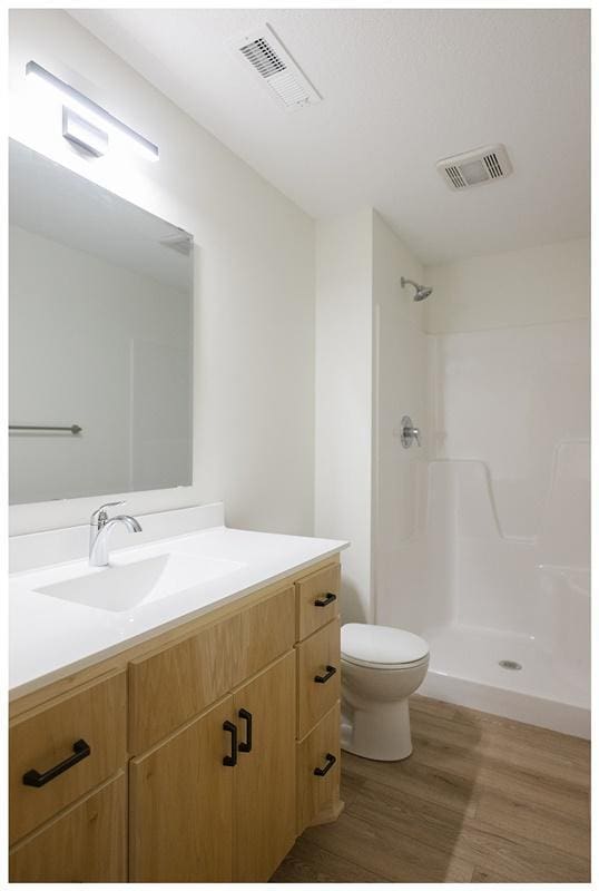 bathroom with vanity, toilet, wood-type flooring, and a shower