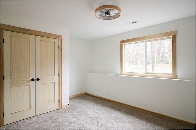 unfurnished bedroom with light carpet and a closet