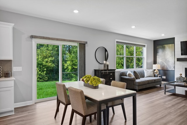 dining area featuring a wealth of natural light, light hardwood / wood-style floors, and a large fireplace