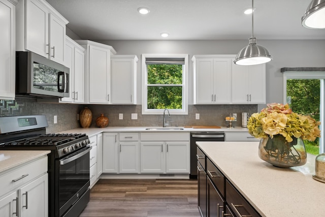 kitchen with sink, backsplash, stainless steel appliances, and white cabinets