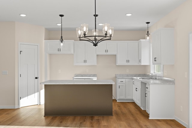 kitchen featuring a center island, sink, hanging light fixtures, light hardwood / wood-style flooring, and white cabinetry