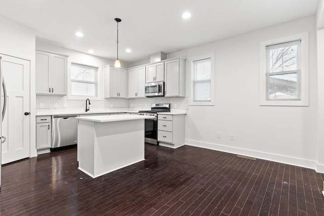 kitchen featuring white cabinetry, sink, hanging light fixtures, stainless steel appliances, and a kitchen island