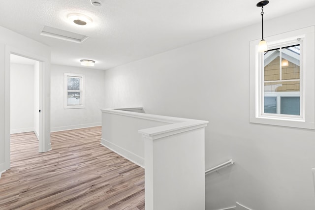 hallway featuring light wood-type flooring and a textured ceiling