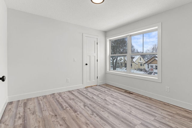 spare room with light hardwood / wood-style floors and a textured ceiling