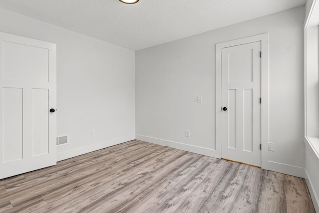 empty room with light hardwood / wood-style floors and a textured ceiling