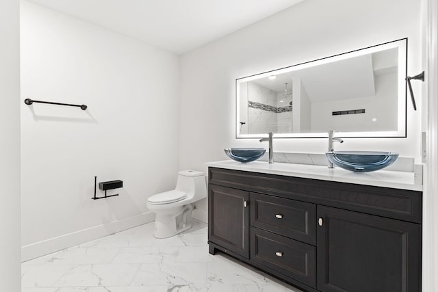 bathroom with tiled shower, vanity, and toilet