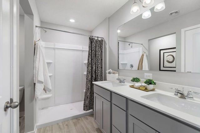 bathroom featuring hardwood / wood-style flooring, vanity, toilet, and walk in shower