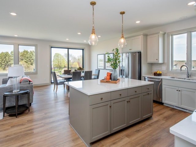 kitchen with hanging light fixtures, gray cabinetry, sink, and stainless steel appliances