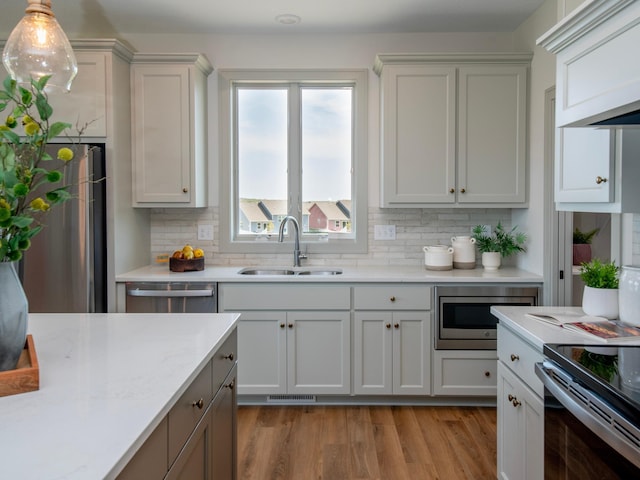 kitchen with appliances with stainless steel finishes, tasteful backsplash, sink, white cabinetry, and hanging light fixtures