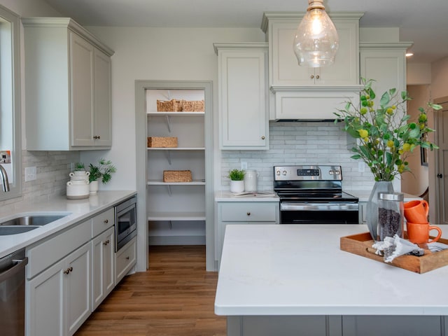 kitchen featuring gray cabinetry, sink, tasteful backsplash, pendant lighting, and appliances with stainless steel finishes