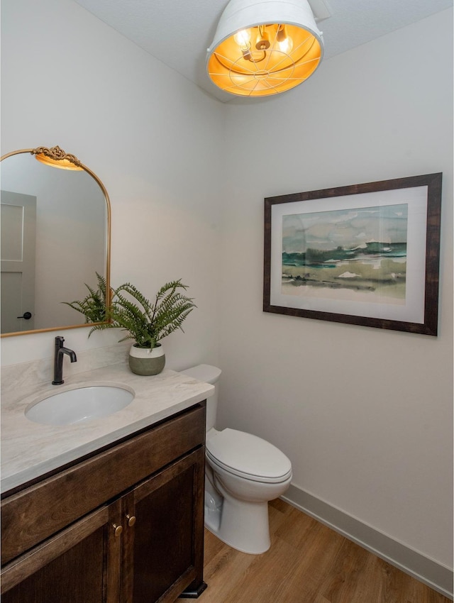 bathroom with wood-type flooring, vanity, and toilet