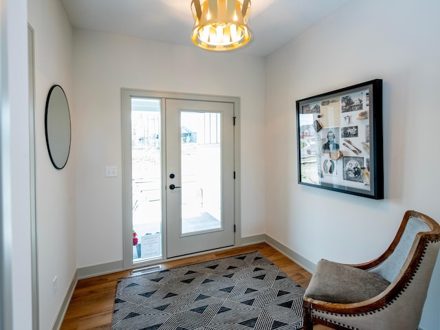 entryway featuring wood-type flooring and an inviting chandelier