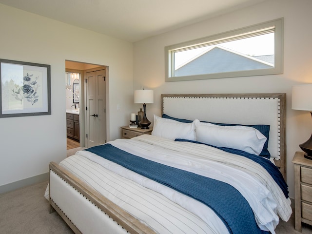 bedroom with ensuite bath and light colored carpet