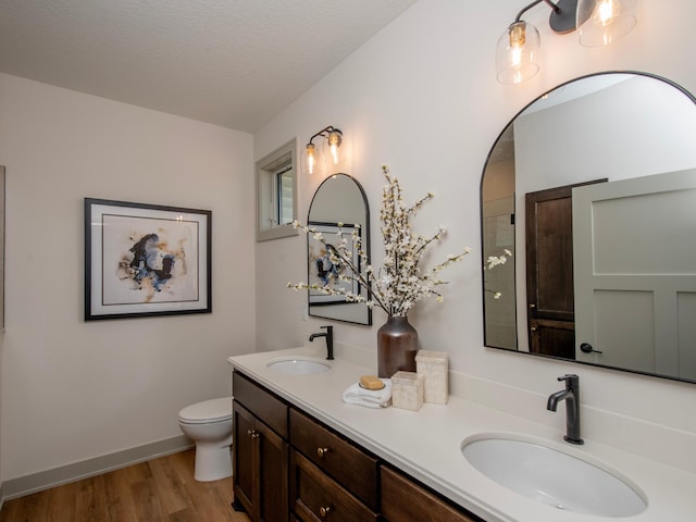 bathroom with hardwood / wood-style flooring, vanity, toilet, and a textured ceiling