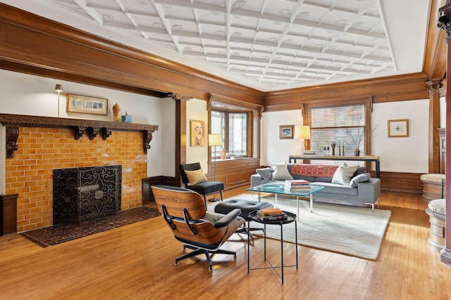 living room with beam ceiling, coffered ceiling, a brick fireplace, light hardwood / wood-style floors, and ornamental molding