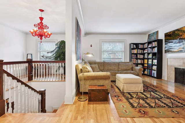 living room featuring a fireplace, light hardwood / wood-style flooring, a notable chandelier, and ornamental molding